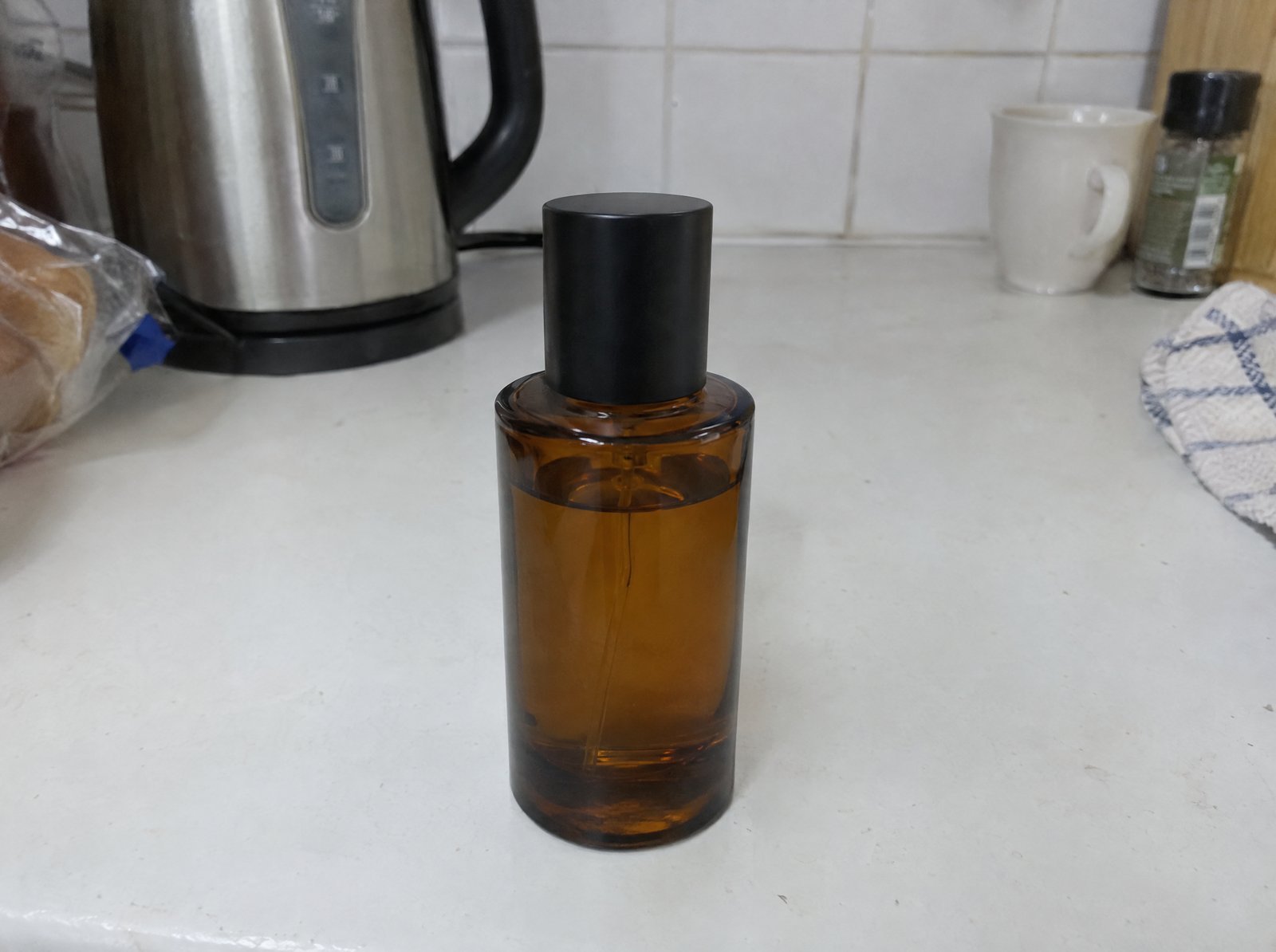 Before: the same amber perfume bottle in a plain snapshot on a kitchen counter
